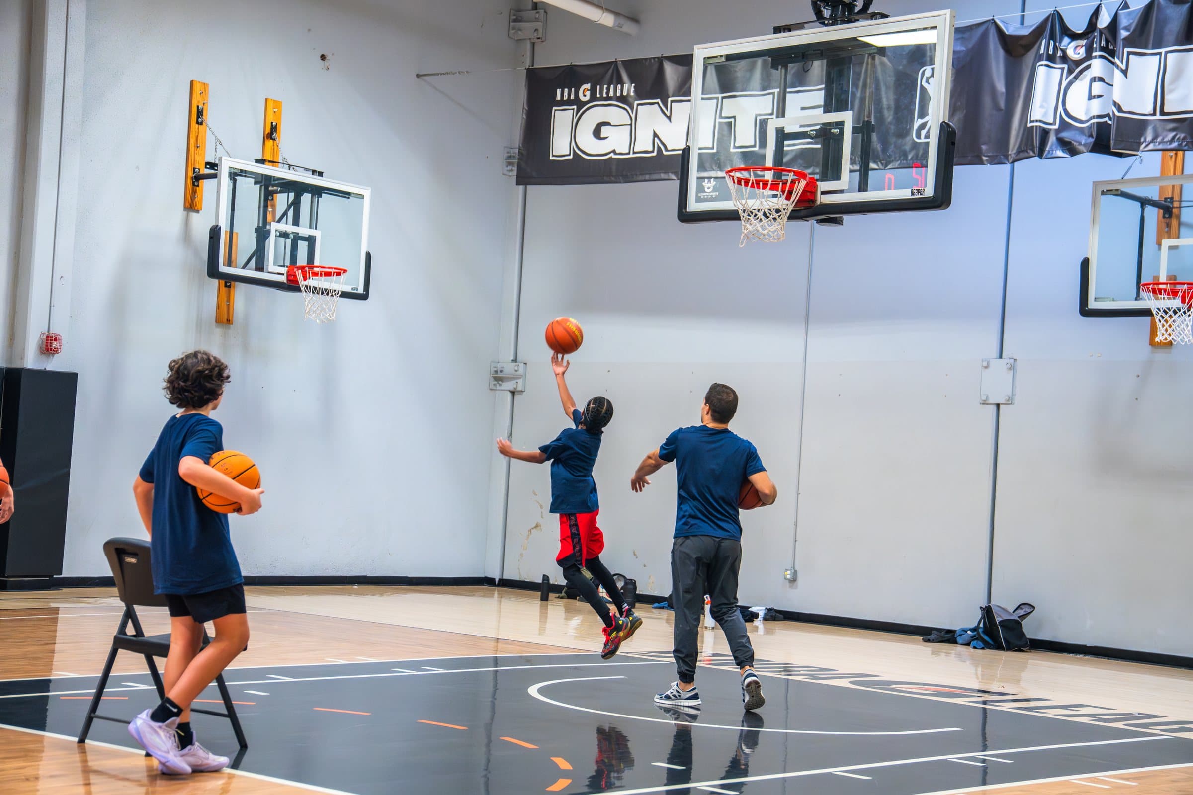 A player goes up for a layup while a coach looks on during ISI Academy basketball.