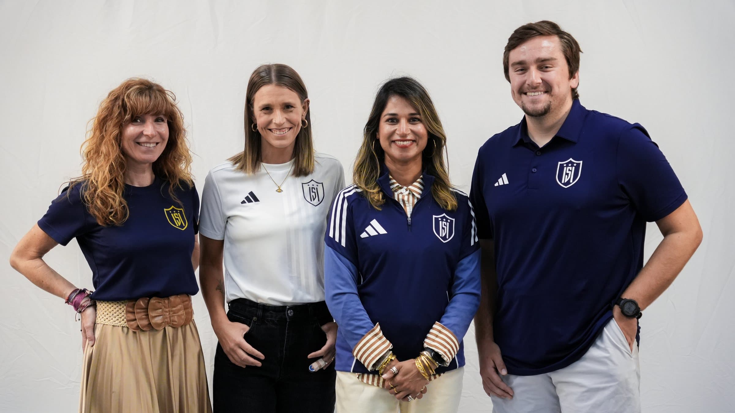 Four ISI Academy coaches and staff standing together, smiling.
